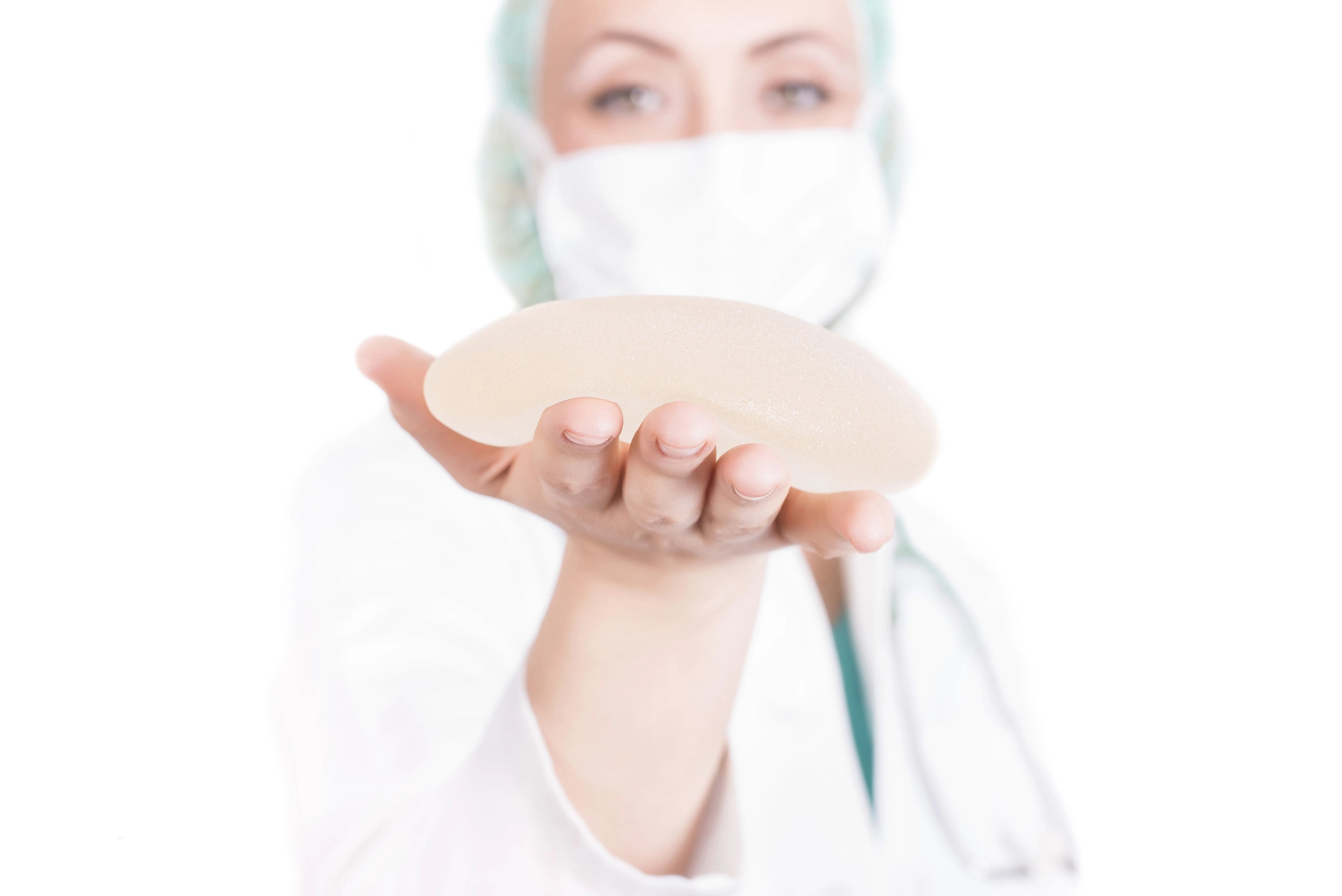 Female plastic surgeon holding a breast implant, focused on the implant in her hands.