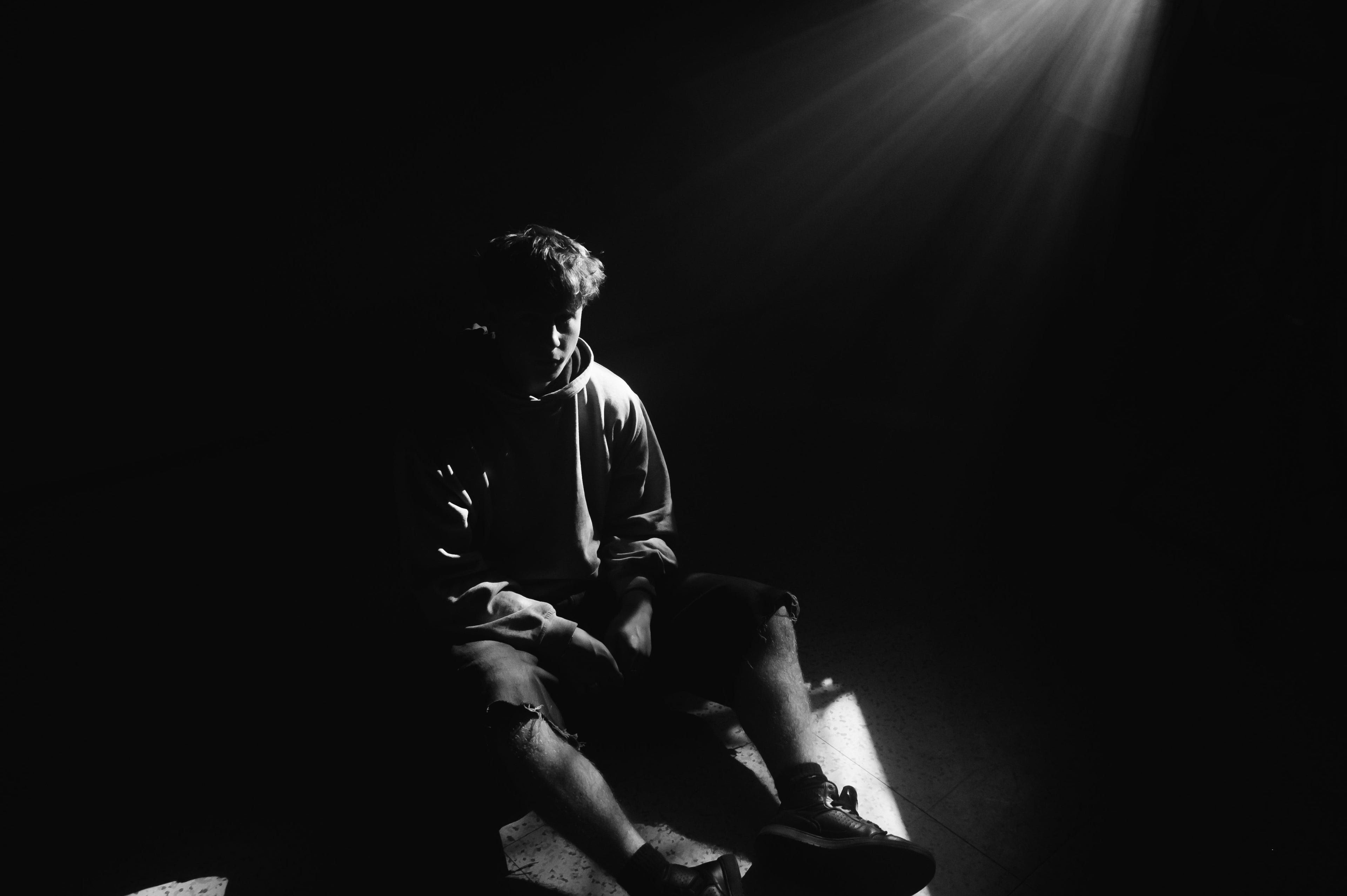 Portrait of a person in darkness with dramatic light rays illuminating one side of the face.